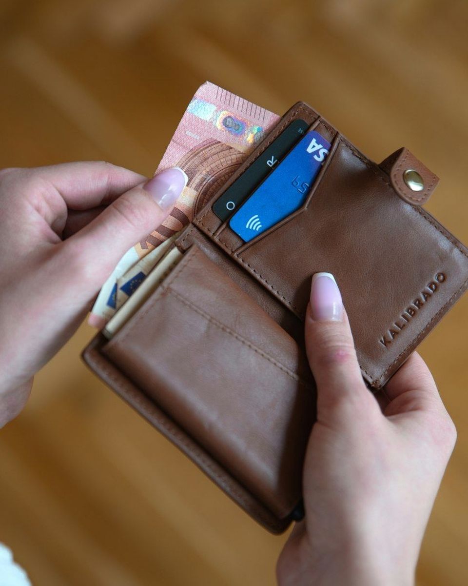 A brown leather wallet held in someone's hand