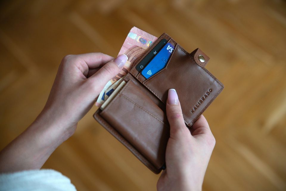 A brown leather wallet held in someone's hand