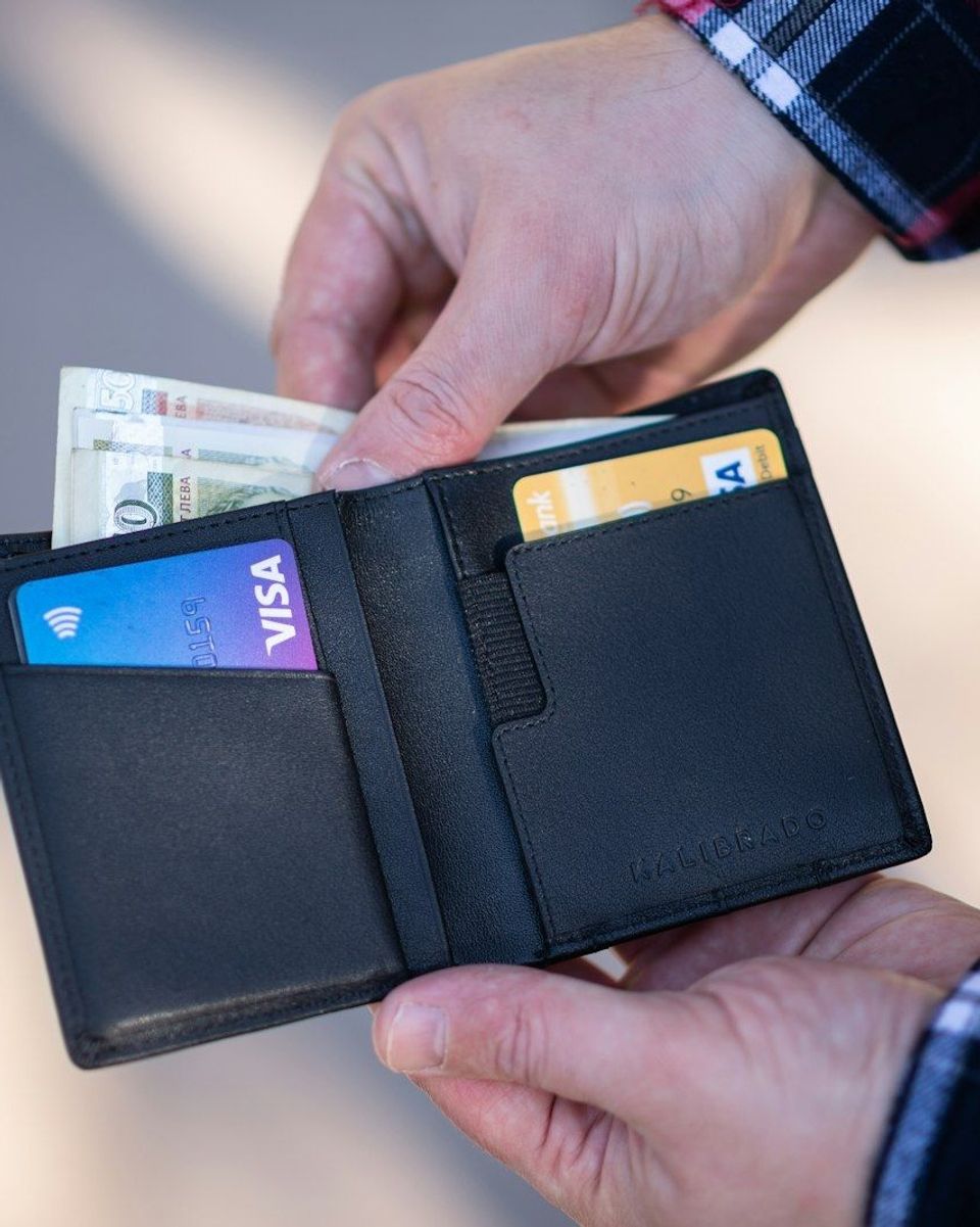 A black leather bifold wallet held in someone's hand