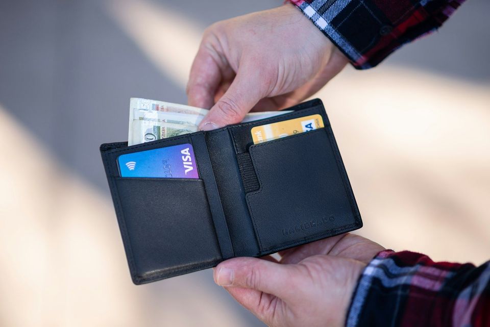 A black leather bifold wallet held in someone's hand