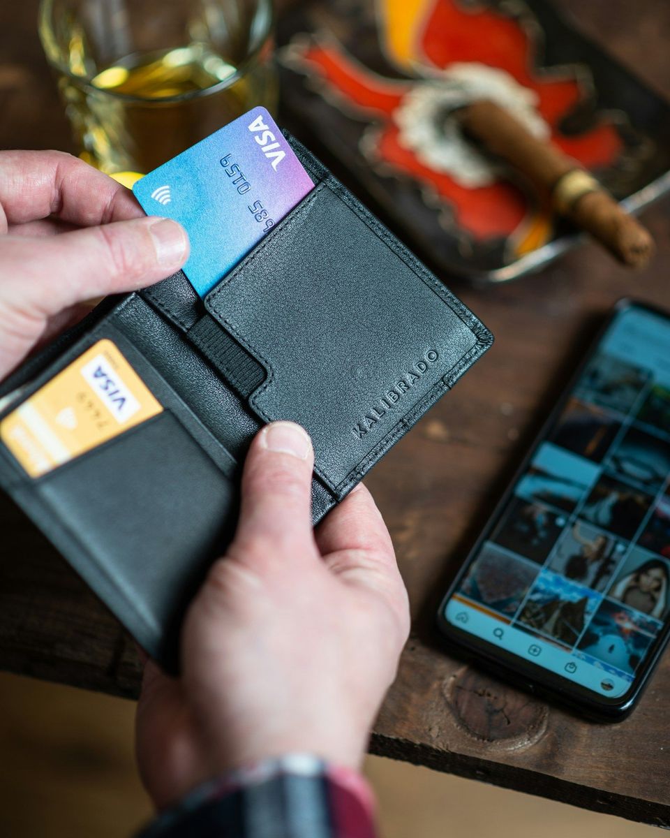 A black leather wallet held in someone's hand