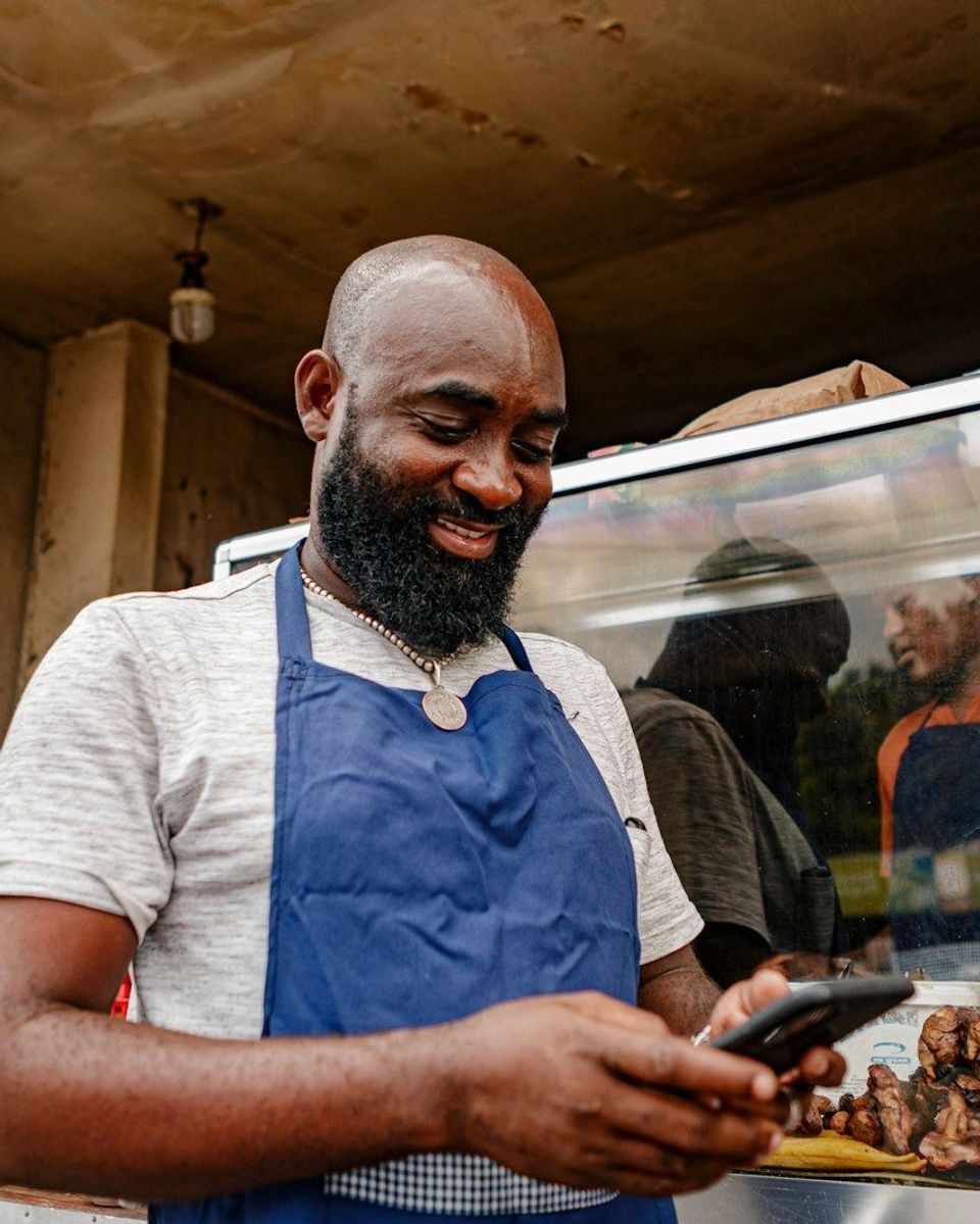 A small business owner in an apron checking their phone