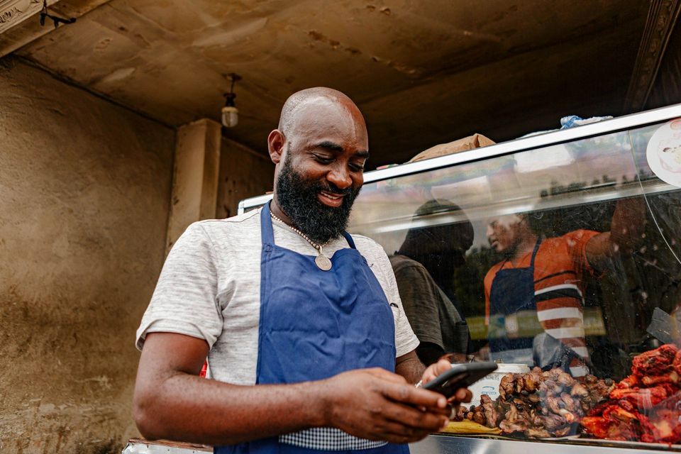A small business owner in an apron checking their phone