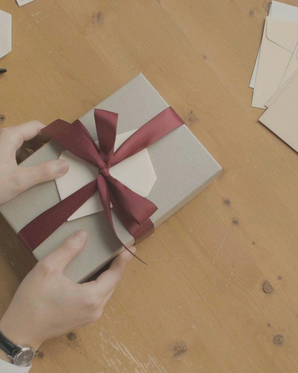 A person opening a gift box with a red ribbon