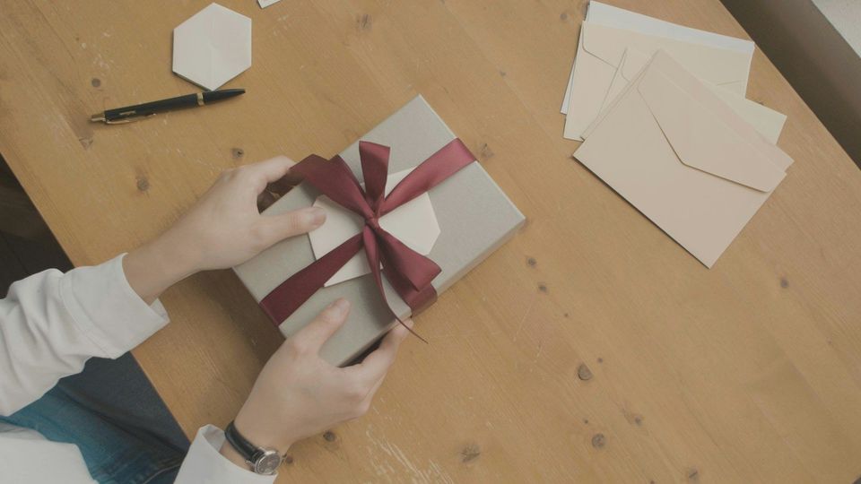 A person opening a gift box with a red ribbon